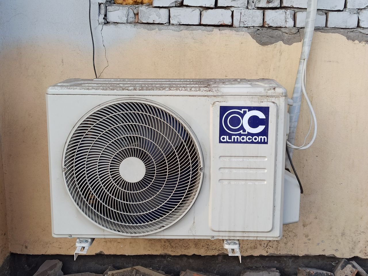 contact-img A well-used outdoor air conditioning unit affixed to a brick wall, showcasing urban climate control.