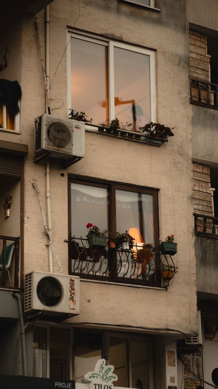 City apartment facade showcasing air conditioners and plants on balconies.