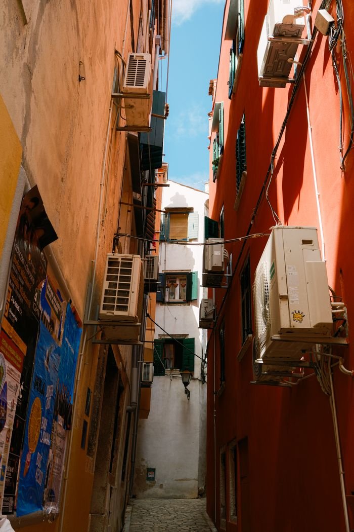 A narrow alley in Croatia lined with colorful buildings and air conditioning units.